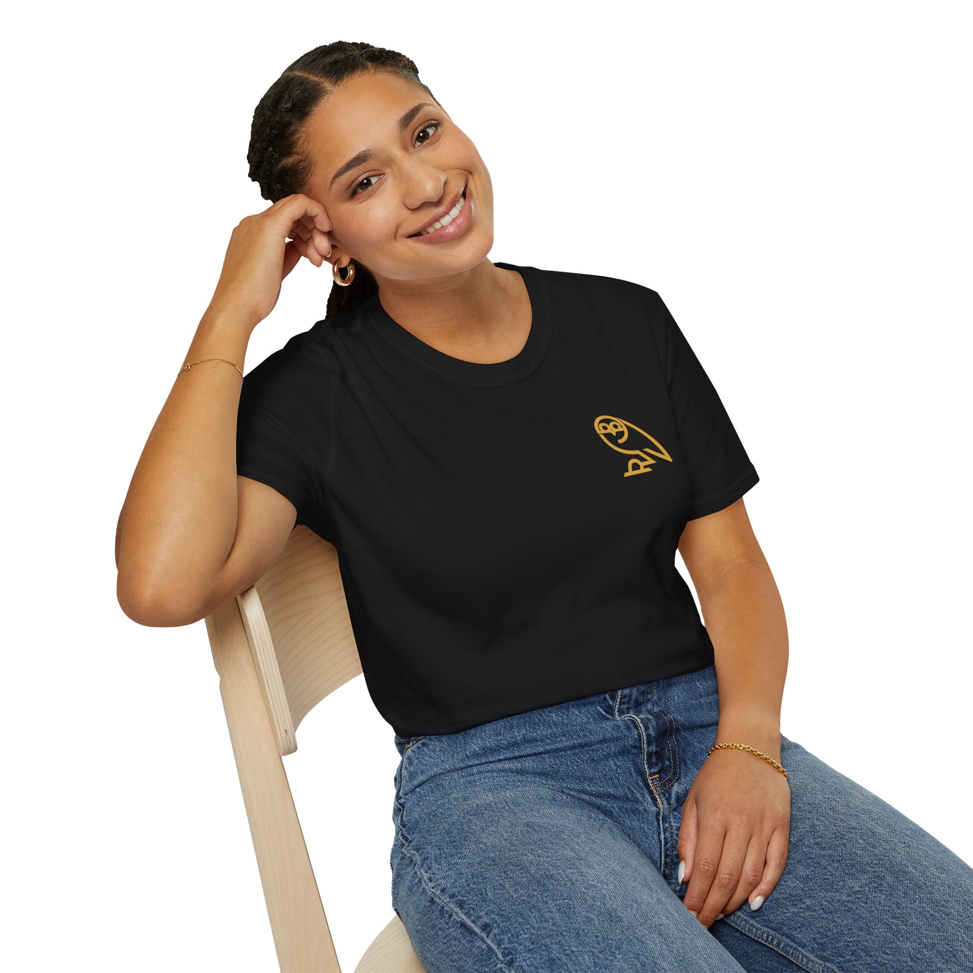 Smiling woman in black t-shirt with gold owl logo sitting on wooden chair against white background