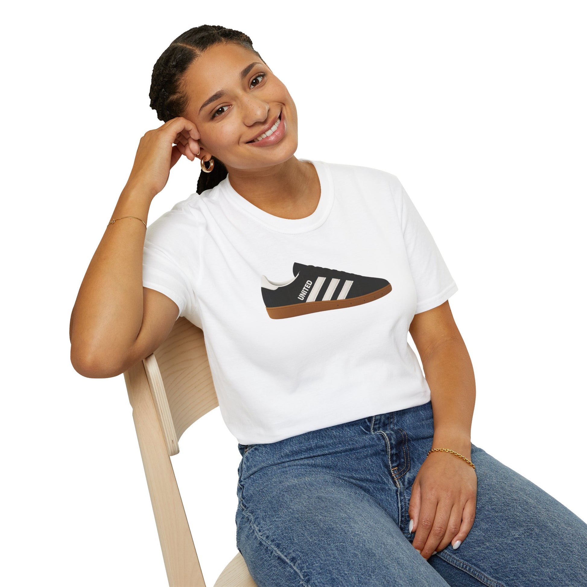 Smiling woman seated on wooden chair wearing white t-shirt with black sneaker graphic and blue jeans