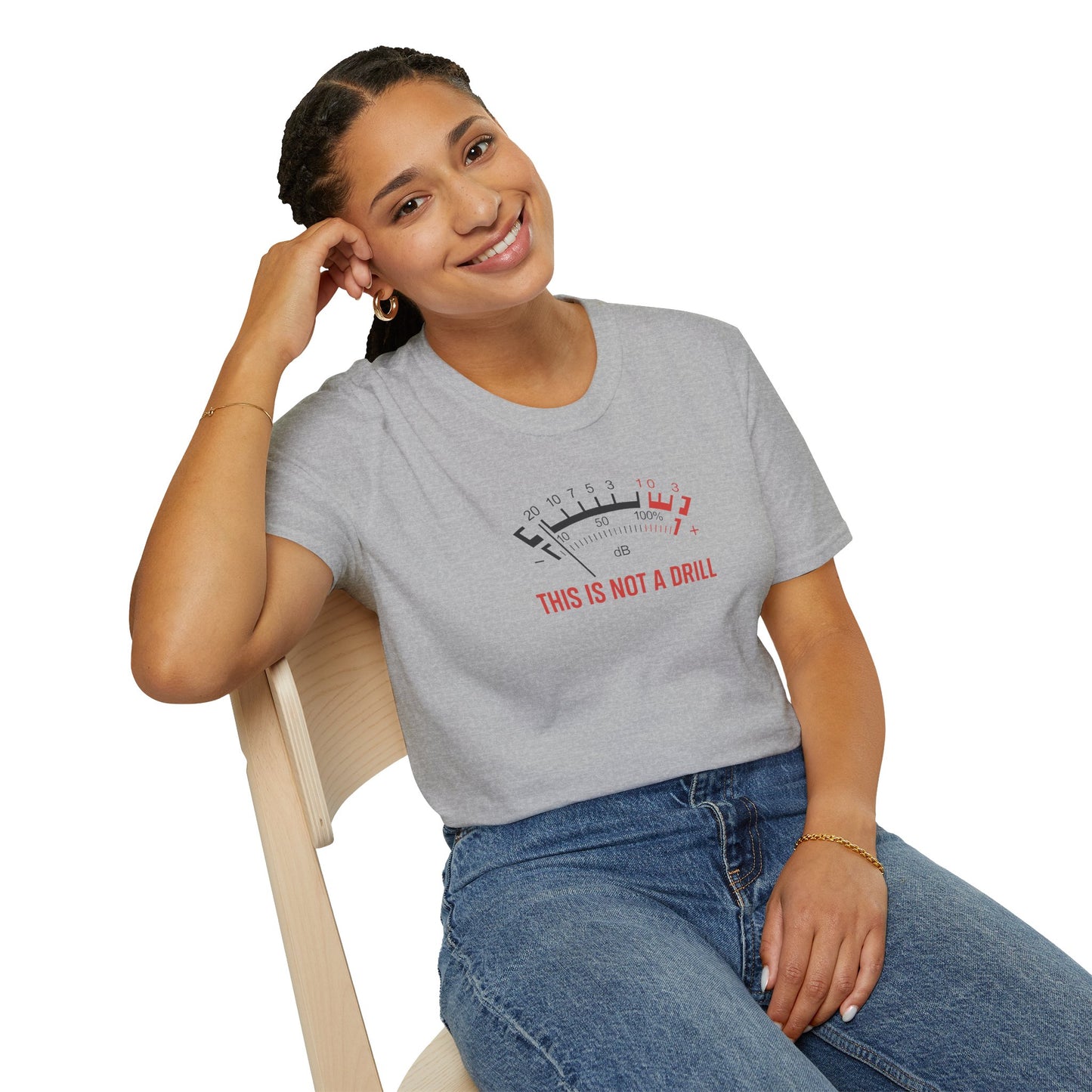 Smiling woman wearing gray T-shirt with volume meter graphic and text This is not a drill, sitting on wooden chair